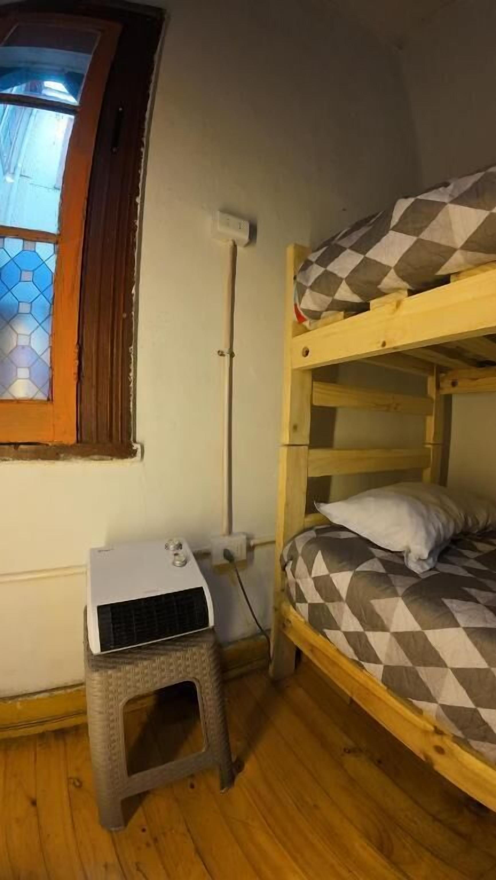 Ein kleines Zimmer mit Etagenbett, einem Fenster mit Buntglas und einem kleinen Tisch mit Klimaanlage.