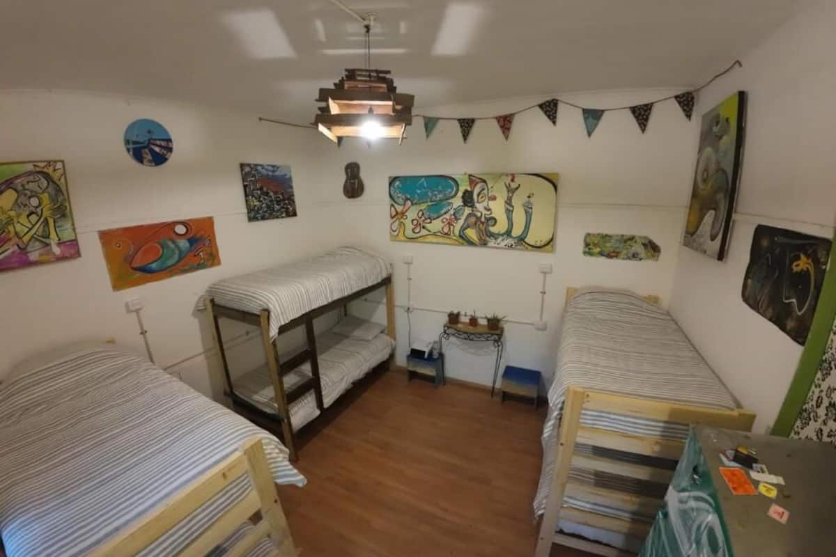 Un dormitorio con literas, un ventilador de techo y diversos cuadros en las paredes.