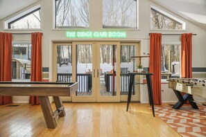 A room with a pool table, foosball table, and a view of a snowy deck outside. - The Ridge at Penn Estates | A 4BR Pocono Retreat (East Stroudsburg)