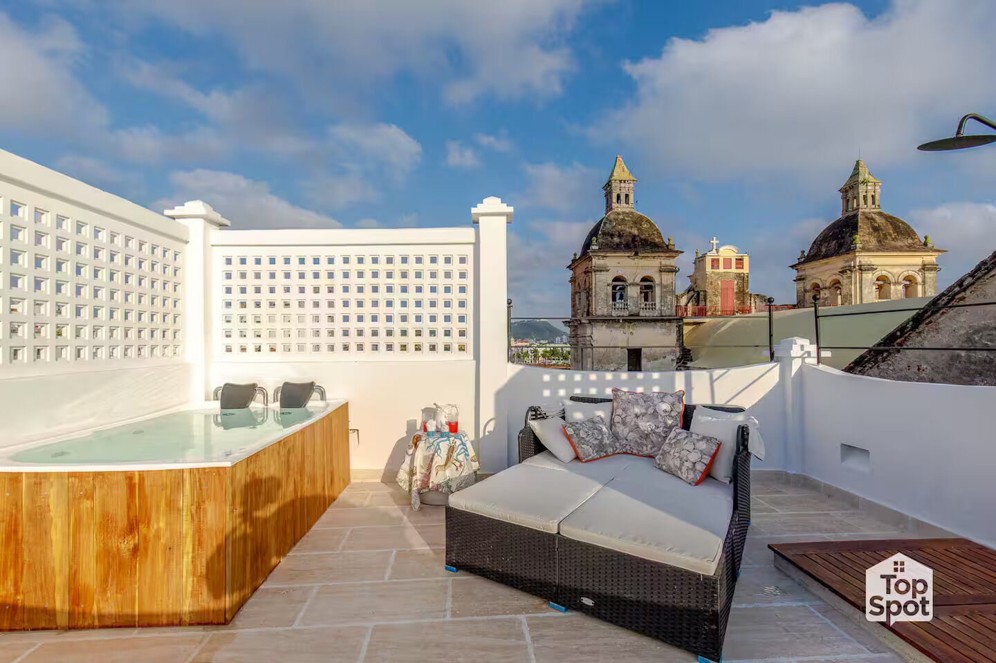 Eine Dachterrasse mit Whirlpool, Sitzgelegenheit und Blick auf historische Gebäude.