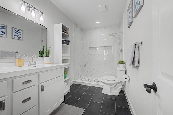 A modern bathroom with a white vanity, a large mirror, a shower, and a toilet. - FriscoDowntown UniversalToyota Soccer3BDFullHome (Frisco)