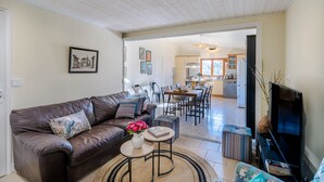 Un salón con un sofá de cuero marrón, una mesa de centro con un jarrón de flores y un televisor sobre un mueble.