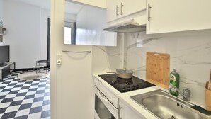 Una cocina con piso a cuadros, estufa, pileta y alacenas.