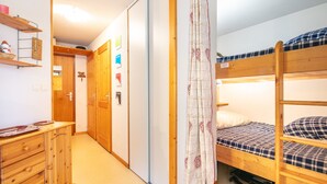 A bunk bed room with a wooden dresser, a curtain, and a door with a sign. - Marvel Morillon - 10 min de la station (Morillon)