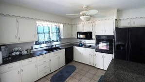 A kitchen with white cabinets, a black refrigerator, a microwave, an oven, and a sink. - Cute 4 Bed house - Central Tulsa with Fenced back yard (Tulsa)