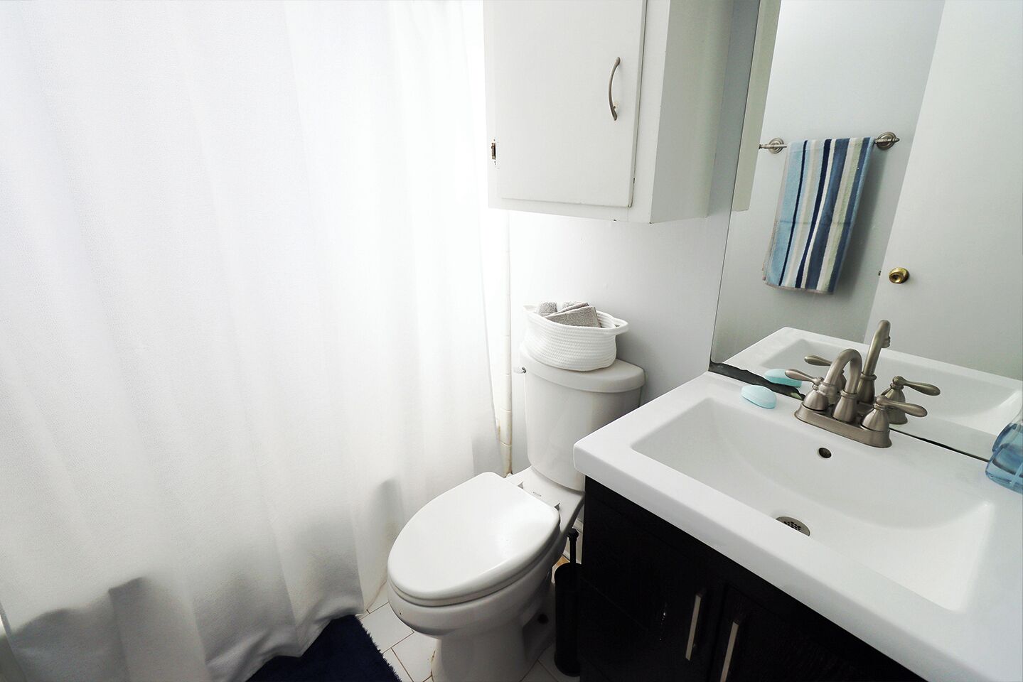 Une salle de bain comprenant des toilettes, un lavabo avec un miroir et un porte-serviettes.