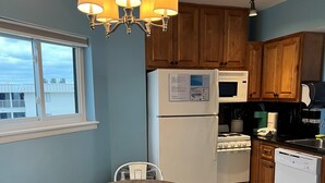 A kitchen with a dining table, chairs, a refrigerator, microwave, stove, and cabinets. - Cozy Corner Studio Unit - Perfect for 2! (Gulf Shores)