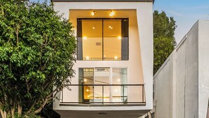 Ein modernes, zweistöckiges Haus mit Garage, Balkon und einer Treppe, die zum zweiten Stock führt.