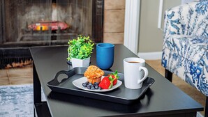 Ein Tablett mit einem Muffin, Erdbeeren und Blaubeeren auf einem Tisch in der Nähe einer Couch mit gemustertem Bezug.