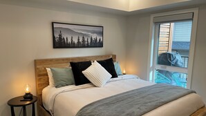 Una camera da letto con un letto in legno, un comodino con una lampada, un quadro appeso alla parete e una finestra vista esterna.