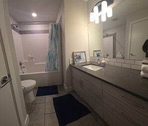 A modern bathroom with a bathtub, toilet, sink, and a large mirror.