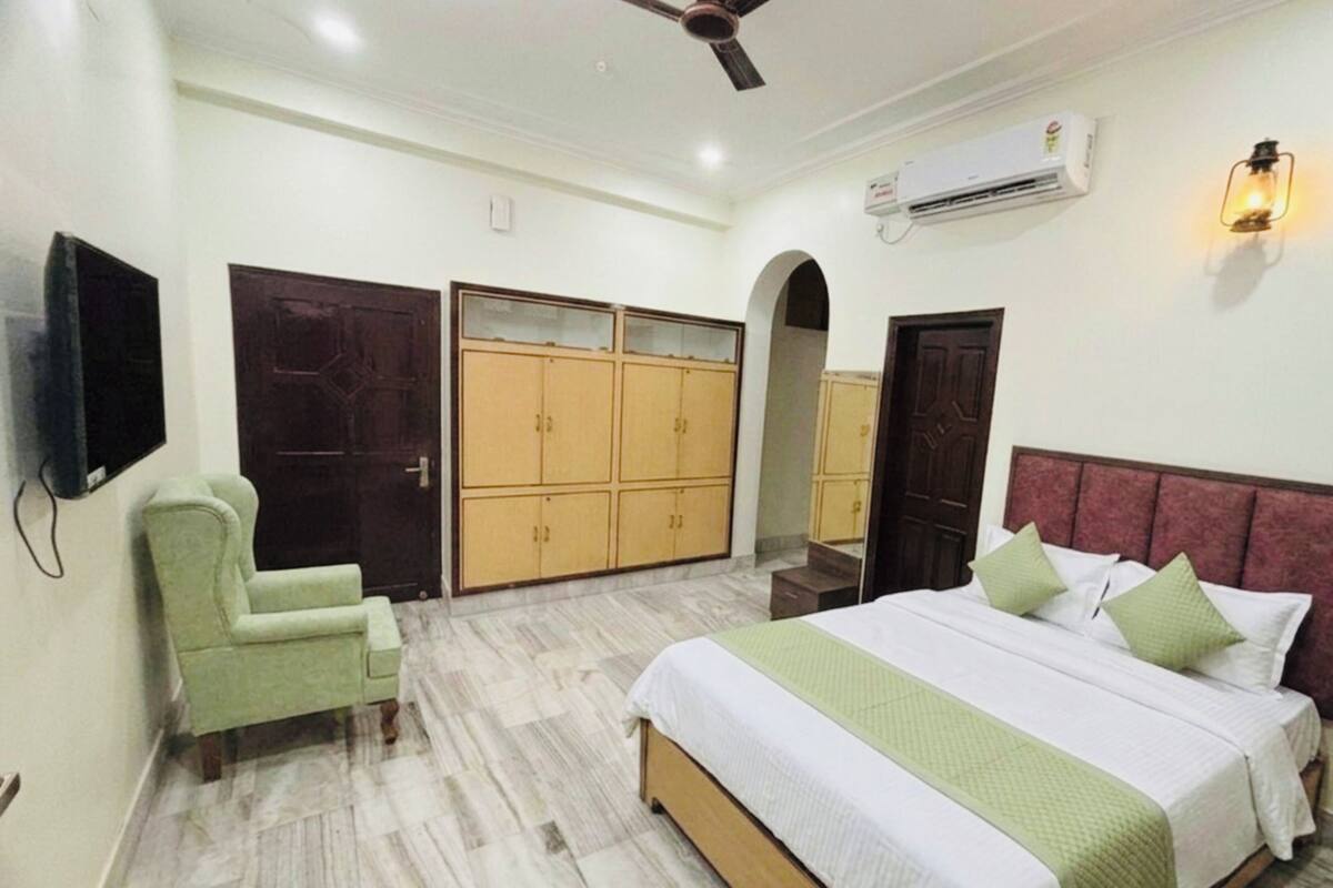 A bedroom with a bed, a chair, wardrobes, an air conditioner, and a ceiling fan.