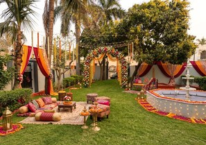 A garden with a seating area, a fountain, and a decorated archway. - The Omaya Kashi (Varanasi)