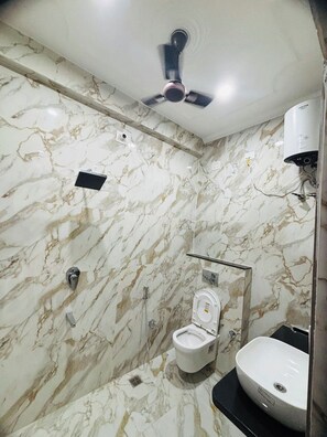 Baño con inodoro, lavabo y ventilador de techo.