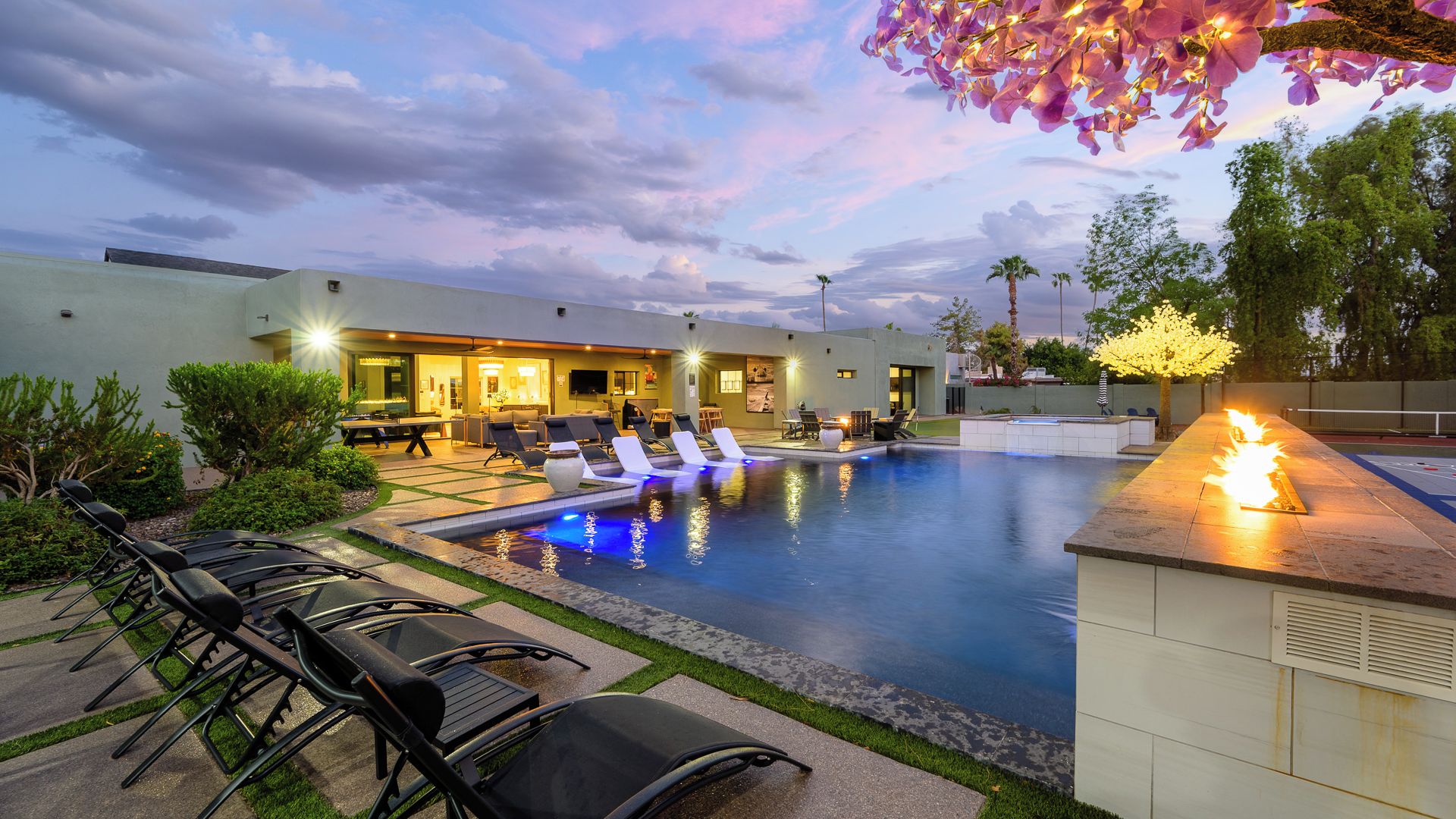 A pool area with lounge chairs, a bar, and a building with outdoor seating.