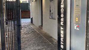Un corridoio con pavimento in pietra, un cancello in metallo nero e una targa che indica Lyon Street Residences.