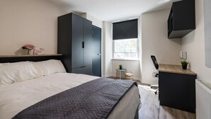 Una camera da letto moderna con un letto, una scrivania, una sedia, un termosifone e una finestra.