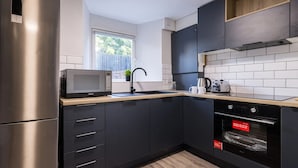 Una cucina moderna con frigorifero in acciaio inox, forno a microonde, lavello e forno integrato.