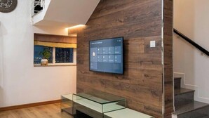 Een modern interieur met een houten wand, een wandgemonteerde televisie en een glazen bank.
