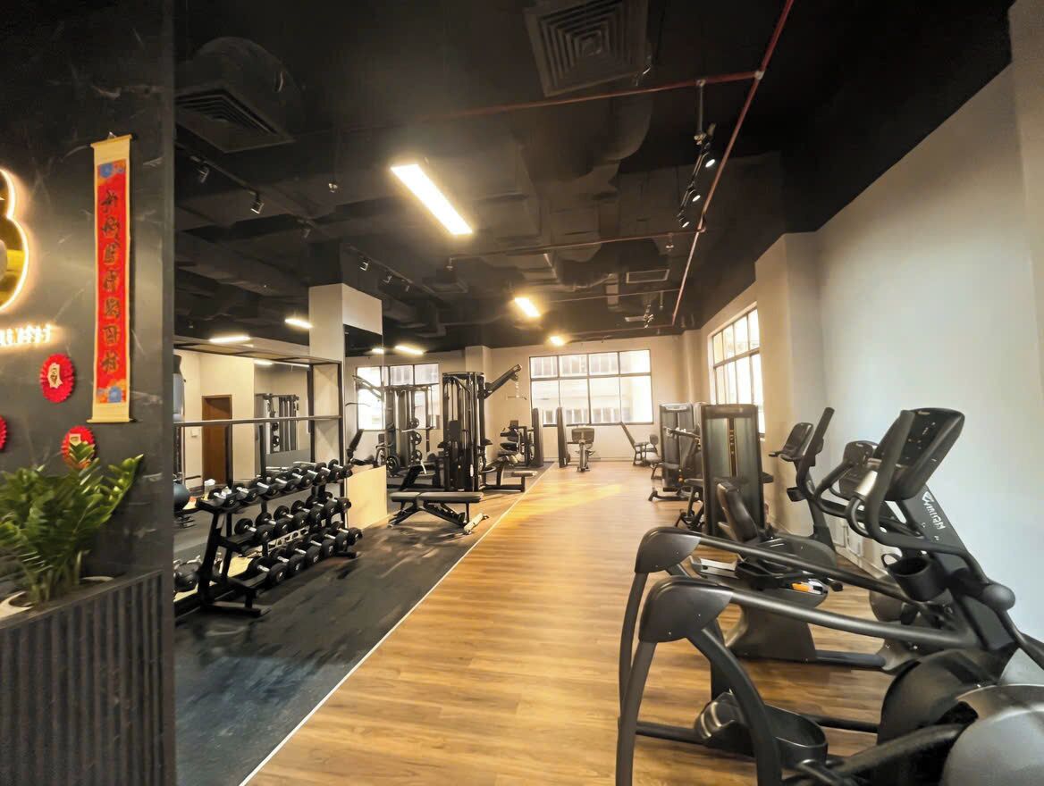 A gym with exercise equipment, a wooden floor, and large windows.