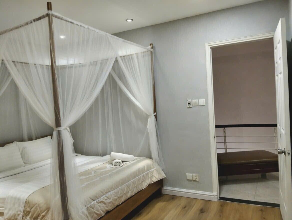 A bedroom with a four-poster bed, a walk-in closet, and a door leading to a balcony.