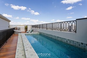 A swimming pool with a wooden deck and tiled walls, surrounded by a black metal fence. - Apt in a Build. w/ a Rooftop Pool, Just 350m From the Metro - Ipis (São Paulo)