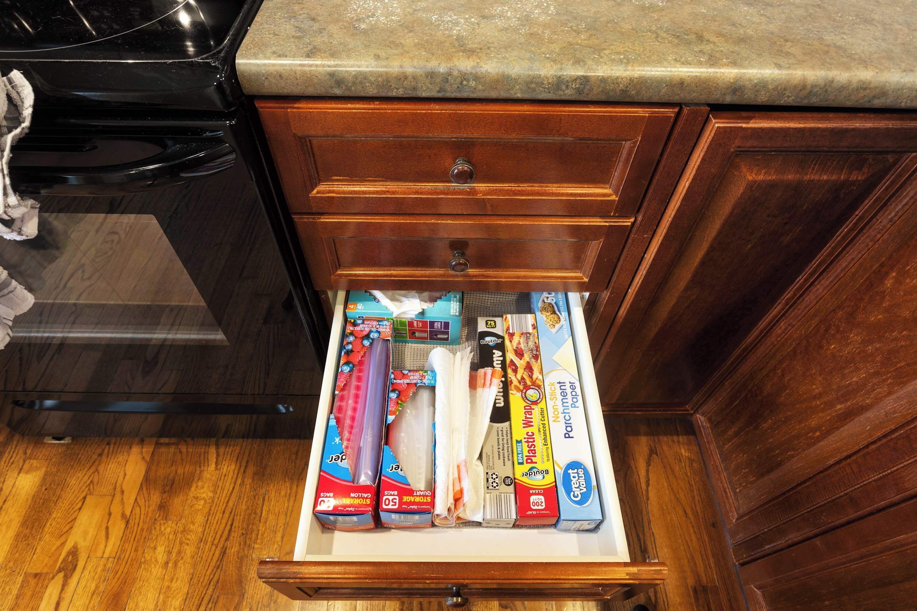 Un cajón de cocina con diversos utensilios, como papel film, una caja de bicarbonato de sodio y una caja de toallas de papel.