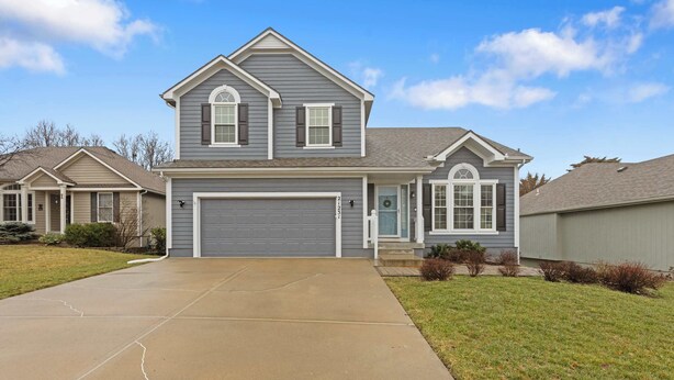 A two-story house with a gray exterior, a garage, and a driveway leading to the front door.