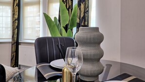 Een eettafel met een zwarte stoel, een glas met een lepel, een gestreepte vaas en een potplant.