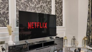 Een moderne woonkamer met een grote flatscreen-tv waarop het Netflix-logo te zien is.