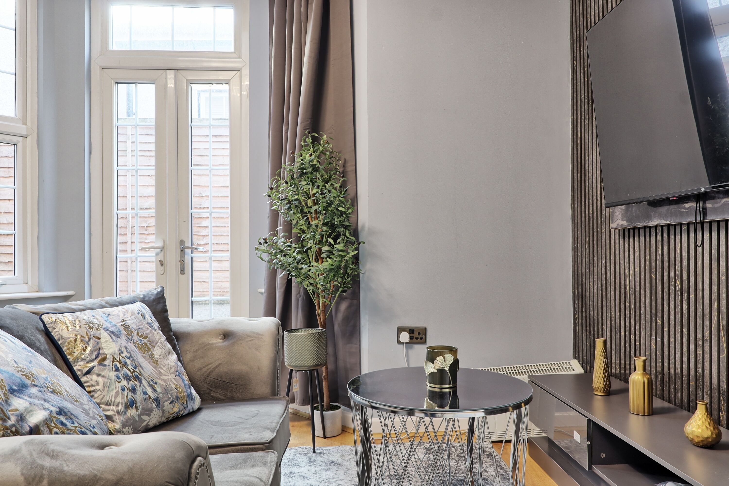 A modern living room with a sofa, a round coffee table, and a TV mounted on the wall.