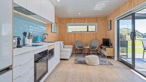 Moderni keittiö, jossa on valkoiset kaapit, sisäänrakennettu uuni ja suuri ikkuna, josta avautuu kaunis maisema.