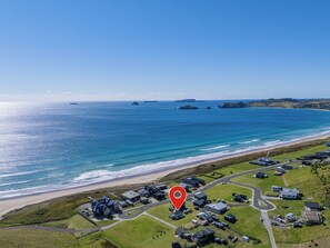Vista aérea de una zona costera con un marcador rojo que indica una ubicación específica.
