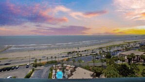 A coastal hotel with a pool, parking, and a view of the beach and ocean. - Two Pina Coladas at San Luis Resort (Galveston)