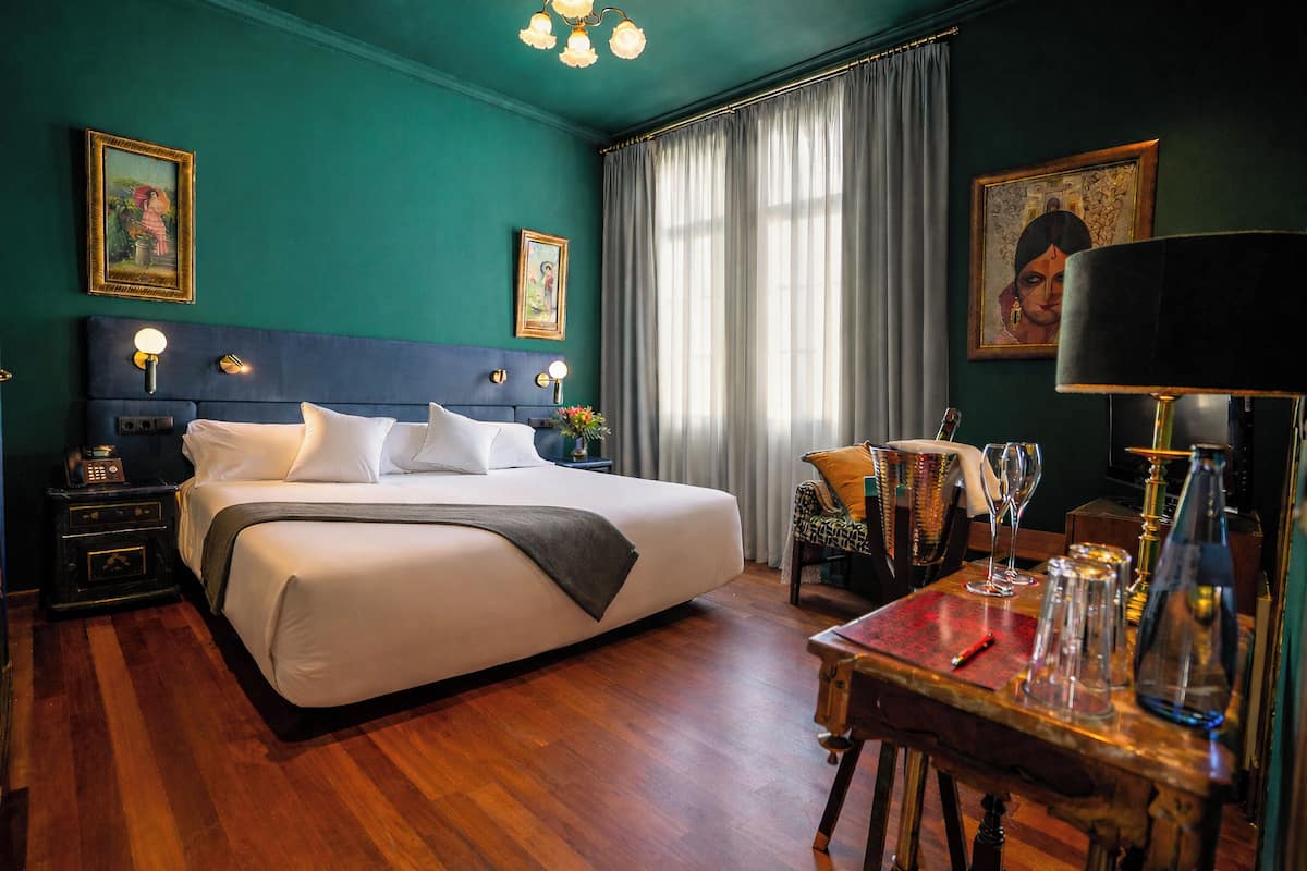 Une chambre d’hôtel avec un grand lit, une table de chevet, une table avec des verres et une chaise.