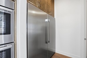 Un refrigerador de acero inoxidable con un gabinete superior de madera en una cocina.