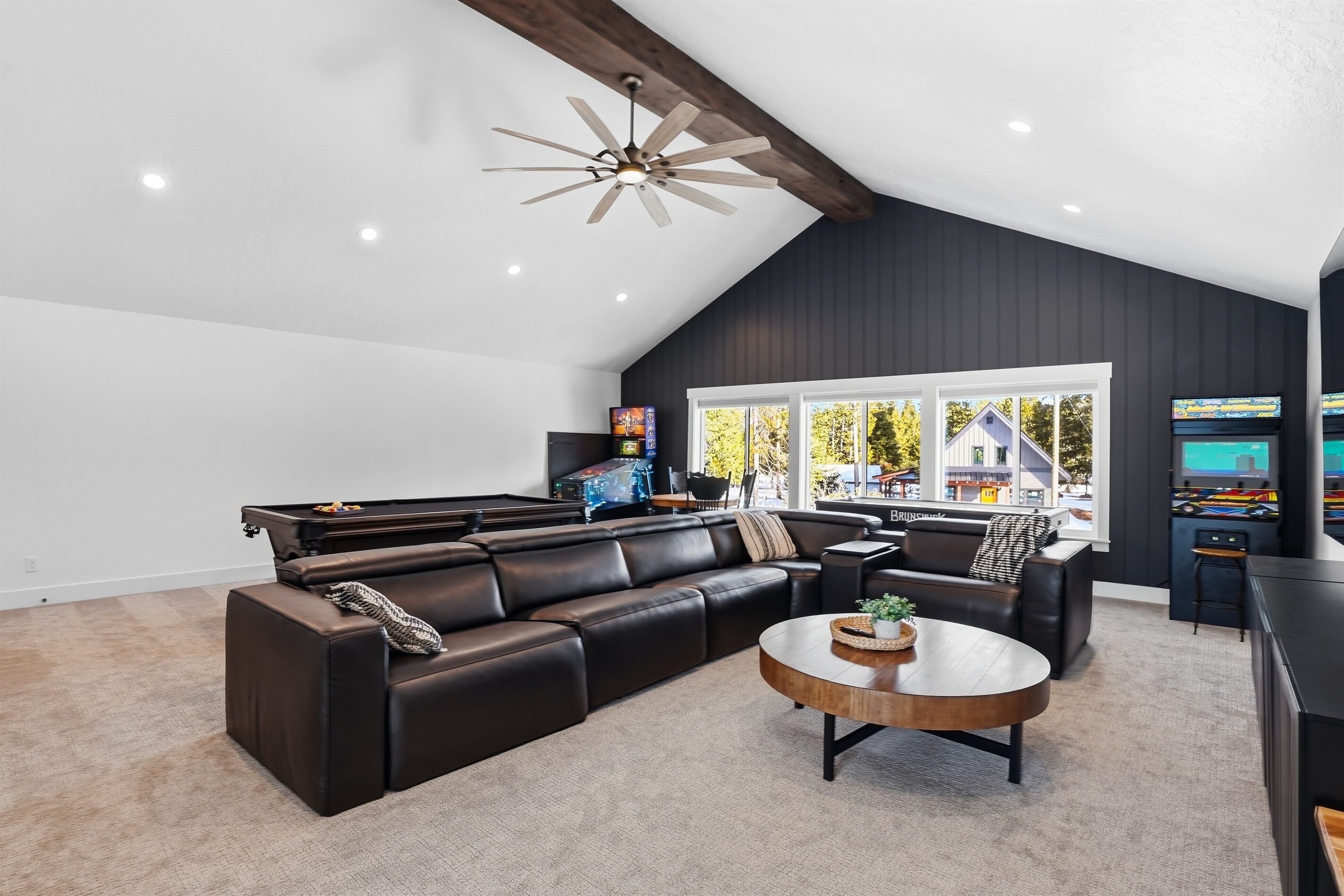 Un salon moderne avec un canapé d’angle, une table basse et un ventilateur de plafond.