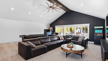 Un salon moderne avec un canapé d’angle, une table basse et un ventilateur de plafond.
