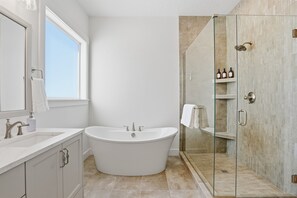 Un baño moderno con una bañera independiente, una ducha con mampara de vidrio y un amplio ventanal que proporciona luz natural.