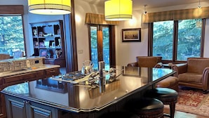 Een ruime woonkamer met een groot eiland, donker houten vloeren en een gezellige zithoek.