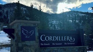 Een bord voor Cordillera met een logo en de tekst 'The Ranch The Summit The Territories' tegen een achtergrond van besneeuwde grond en bergen.