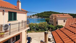 A coastal residential area with terracotta-tiled roofs, a clear blue sky, and a marina in the background. - Sea View Apartments Kukljica (Kukljica)
