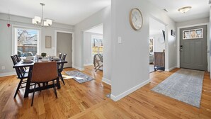 Un comedor amplio con una mesa y sillas de madera, un candelabro y un reloj en la pared.
