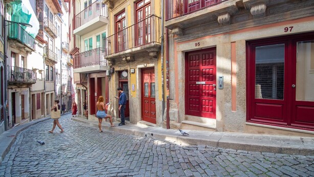 Eine Kopfsteinpflasterstraße mit Gebäuden, die rote Türen und Balkone haben.
