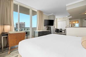 A modern hotel room with a large bed, a desk, a flat-screen TV, and a balcony with a city view. - Studio Condo with in-unit W/D, Free Parking, and Hotel Amenities (Miami)