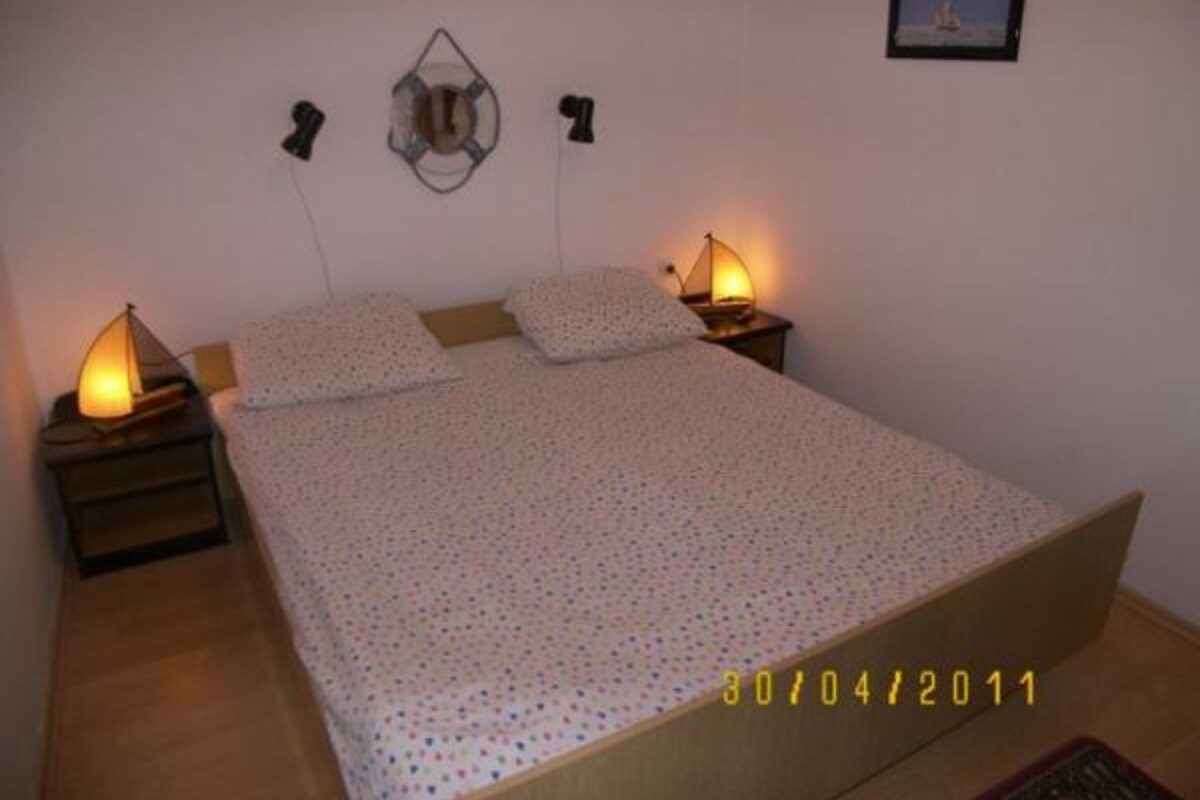 A bedroom with a bed, two bedside lamps, a wall clock, and a framed picture.