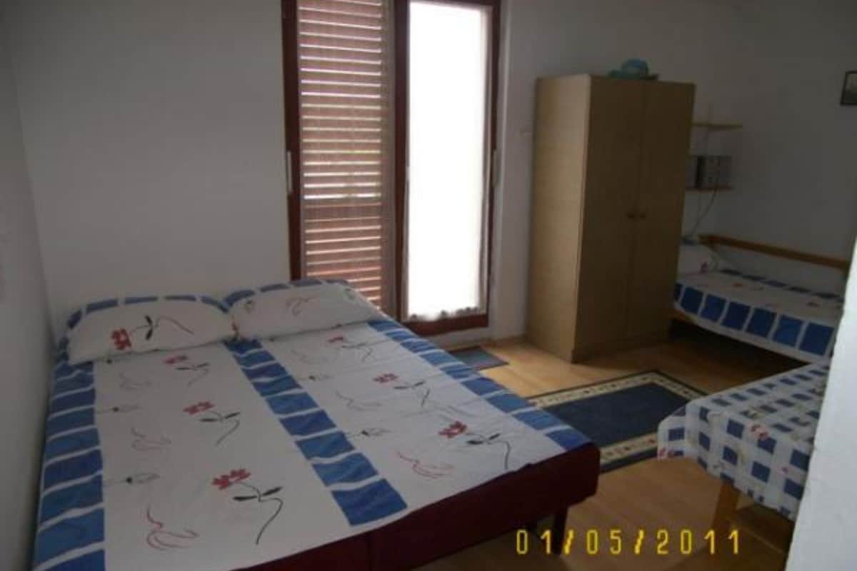 A bedroom with a bed, a wardrobe, and a window with blinds.