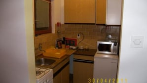 A compact kitchen with a gas stove, a microwave, and a sink. - Apartments Zlatko (Vodice)