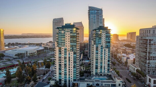 A high-rise building complex with multiple floors, surrounded by other buildings and a body of water in the background. - Modern & Spacious 1 br + bonus rm 2 bthrm apartment in Marina District high rise (San Diego)