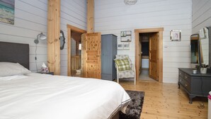 Una camera da letto con un letto grande, pareti in legno, un comò e una sedia.